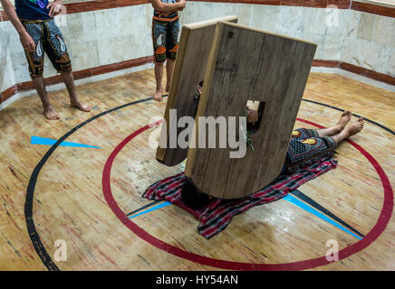Young man training with heavy shields called sang in Zoorkhaneh (House of Strength), traditional gymnasium in Yazd, capital of Yazd Province of Iran Stock Photo