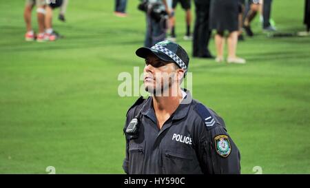 An Australian police man on duty facing the crowds in a stadium Stock Photo