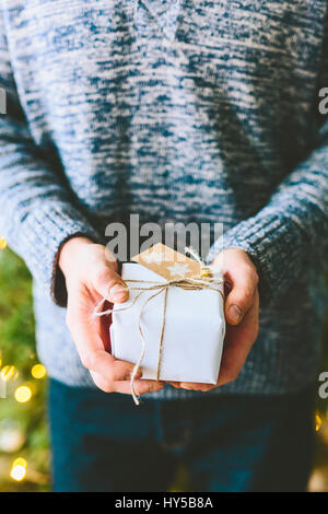 Finland, Man holding christmas gift against christmas tree Stock Photo