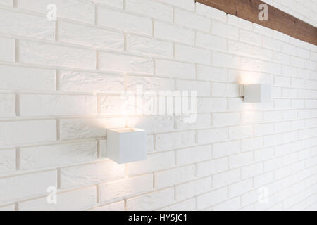 White brick wall with two lights and wooden beam Stock Photo