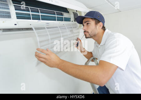 portrait of mid-adult male technician repairing air conditioner Stock Photo