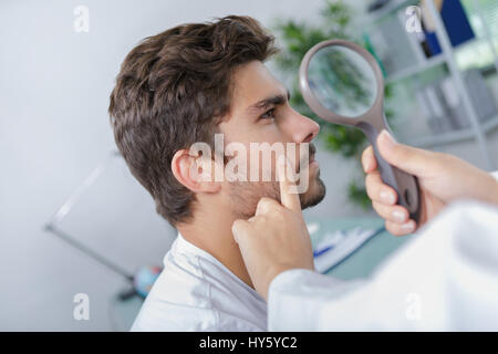 close-up of doctors hands checking mans moles Stock Photo