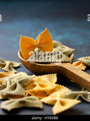 Traditional italian pasta farfalle in a wooden spoon on a blue background Stock Photo