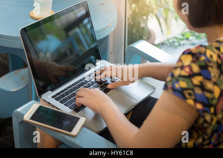 Young Asian woman working online at home with laptop computer. Freelance and outsource worker activity concept. Stock Photo
