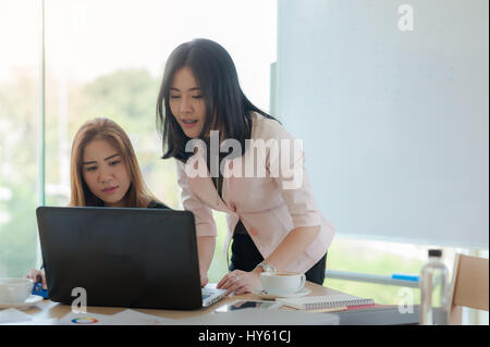Young Asian business workers working together with laptop computer in office. Business startup teamwork and brainstorm concept Stock Photo