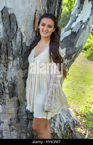 Eighteen year old girl standing by a tree, La Jolla, California Stock Photo