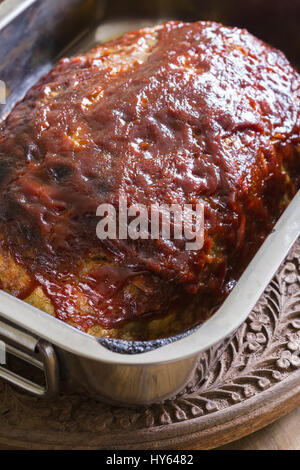 Classic American meatloaf made with ground beef oatmeal onions and a ketchup brown sugar and mustard glaze in a steel roasting pan hot out of the oven Stock Photo