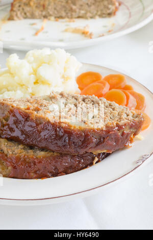 Classic American meatloaf made with ground beef oatmeal onions and a ketchup brown sugar and mustard glaze served with mashed potatoes and carrot coin Stock Photo