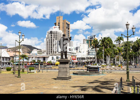 PORT LOUIS, MAURITIUS - NOVEMBER 18, 2016: A statue overlooks the waterfront promenade in front of the he modern business center of Port Louis, Maurit Stock Photo