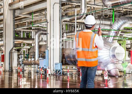 Engineer working in a thermal power plant with talking on the walkie-talkie for controlling work Stock Photo