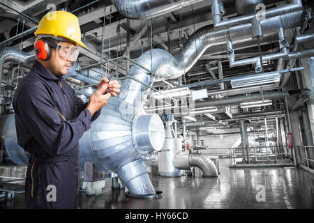 Engineer working in a thermal power plant with talking on the walkie-talkie for controlling work Stock Photo