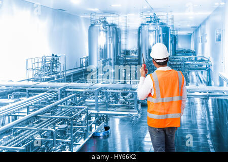 Industrial engineer working in the factory with talking on the walkie-talkie for controlling work Stock Photo