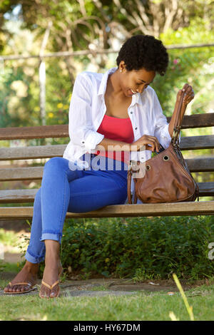 A woman sitting on the ground holding a purse photo – Free Woman