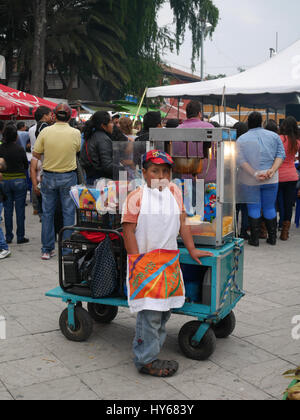 Young child is working selling popcorn next to pop corn machine in Antigua Guatemala Stock Photo