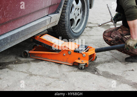 installation of passenger car wheel and replacement on spring tire in cloudy day outdoors Stock Photo