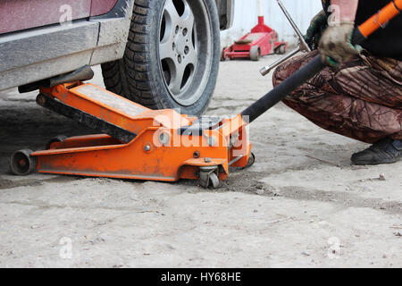 installation of passenger car wheel and replacement on spring tire in cloudy day outdoors Stock Photo