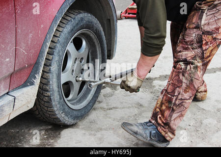 installation of passenger car wheel and replacement on spring tire in cloudy day outdoors Stock Photo