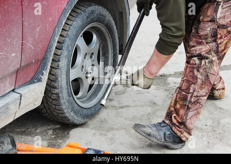 installation of passenger car wheel and replacement on spring tire in cloudy day outdoors Stock Photo