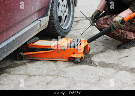 installation of passenger car wheel and replacement on spring tire in cloudy day outdoors Stock Photo