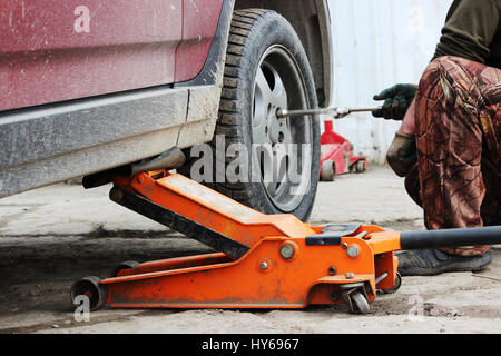 installation of passenger car wheel and replacement on spring tire in cloudy day outdoors Stock Photo