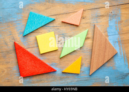 seven colorful tangram wooden pieces, a traditional Chinese puzzle game on a grunge wooden background Stock Photo