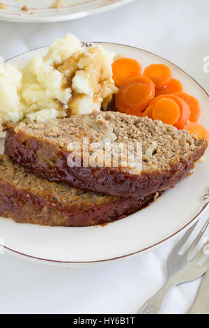 Classic American meatloaf made with ground beef oatmeal onions and a ketchup brown sugar and mustard glaze served with mashed potatoes and carrot coin Stock Photo