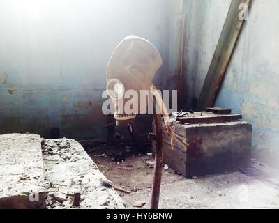 Gas mask hanging on a vertical stick in an abandoned building Stock Photo