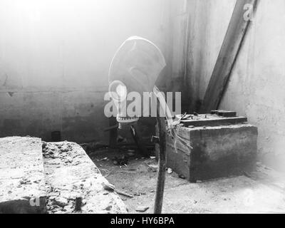 Black and white photo gas mask hanging on a vertical stick in an abandoned building Stock Photo