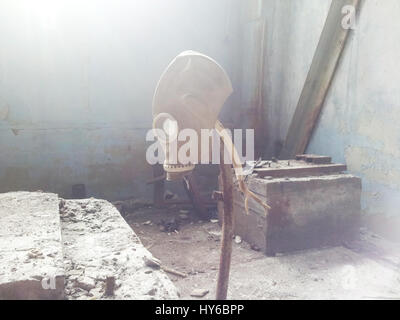 Gas mask hanging on a vertical stick in an abandoned building Stock Photo