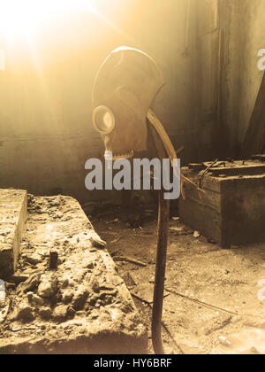 Gas mask hanging on a vertical stick in an abandoned building Stock Photo