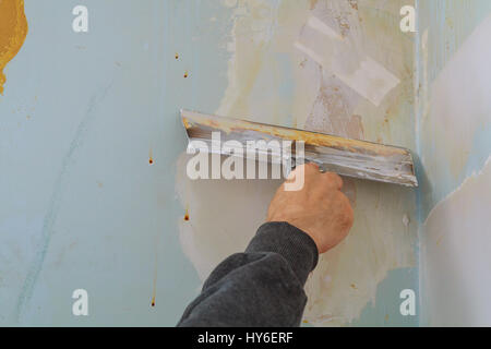 master makes repairs in the apartment and lining the walls with putty wall putty to defective Stock Photo
