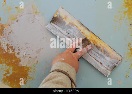 The process of applying the second layer of putty trowel for light plaster walls wall putty to defective Stock Photo