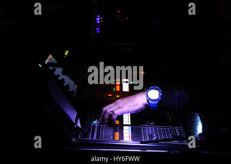 Audioman operating a portable digital sound mixer device to control the output of sounds that came from the stage in a live performance. Stock Photo
