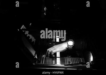 Audioman operating a portable digital sound mixer device to control the output of sounds that came from the stage in a live performance. Black and whi Stock Photo