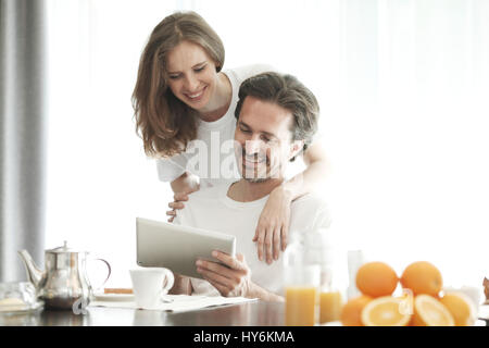 Couple having breakfast at home and using tablet Stock Photo