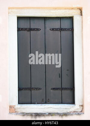 grey shuttered window with metal hinges in a white wall Stock Photo