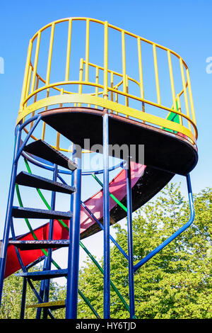 An red, blue and yellow painted old-fashioned spiral children's slide in a public park, London, UK Stock Photo