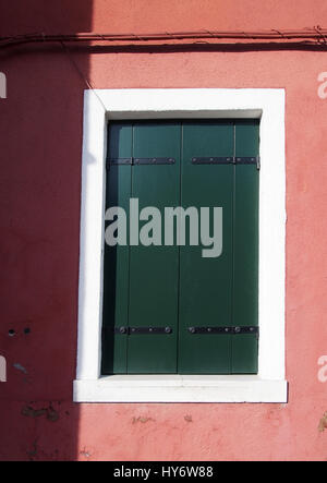 Green shuttered window in a white frame on a pink wall Stock Photo