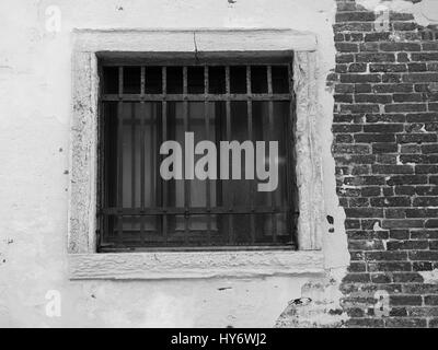 Old barred window on a distressed brick wall Stock Photo