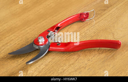 Garden scissors with red handle on background of the wooden table Stock Photo