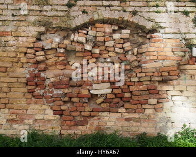 old brick wall with many signs of repair and uneven brickwork Stock Photo