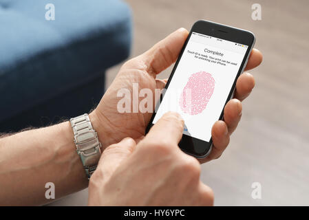 Kiev, Ukraine - March 06, 2016: Man using touch ID scanner of fingerprints on  iPhones 6, developed by Apple corporation. Allows users to unblock the Stock Photo