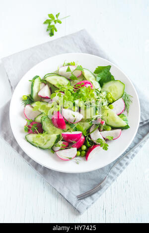 Healthy spring vegetables salad with radish, cucumber, green peas and sprouts, diet, vegetarian, vegan, organic, green food, spring detox snack Stock Photo