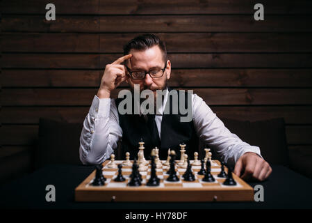 Pensive male chess player in glasses thinking about game strategy. Intelligence competition concept Stock Photo