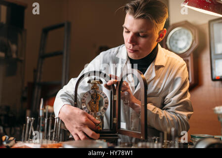 Watchmaker holding old table clock. Antique mechanical watch repairing in the workshop Stock Photo