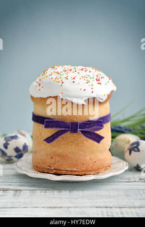 Easter cake on the plate and colorful eggs and flowers on blue background Stock Photo