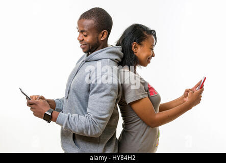 An African man and woman seen using mobile devices inn  a studio setting. Stock Photo