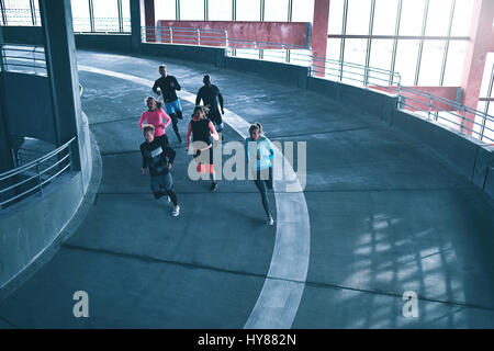 Group of young athletes training in gym and running on race track. Stock Photo