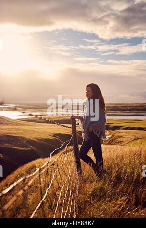 A young women wearing knitwear standing in a dramatic landscape in Iceland Stock Photo