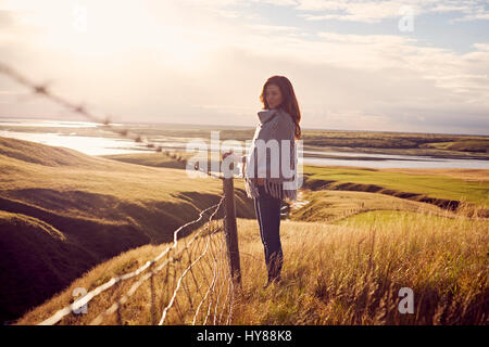 A young women wearing knitwear standing in a dramatic landscape in Iceland Stock Photo